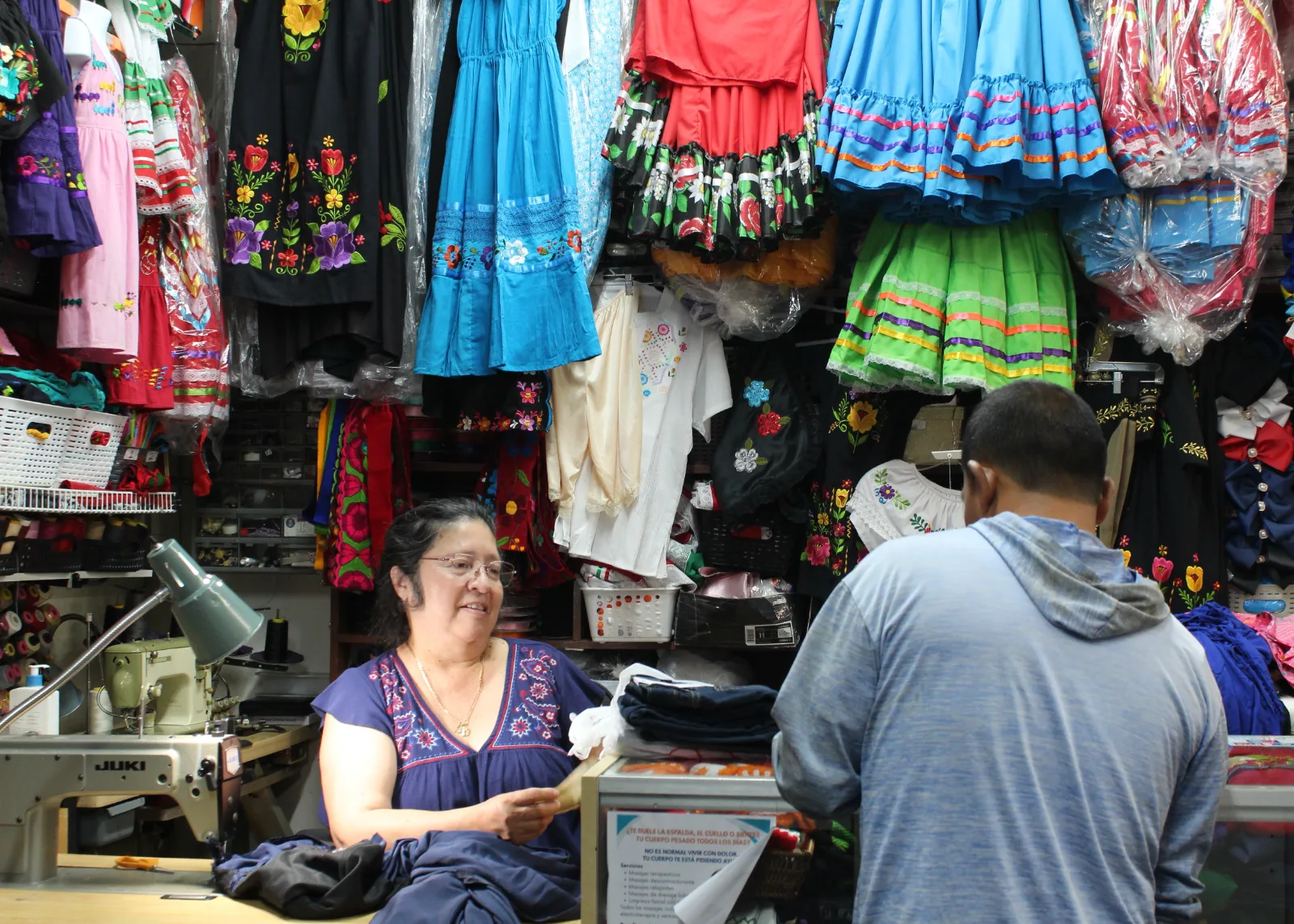 Doña Dora atendiendo a un cliente en el mostrador de costura